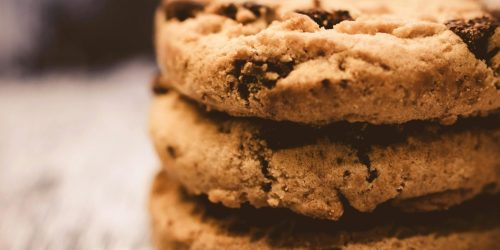 A macro shot of freshly baked stacked chocolate chip cookies creates a cozy dessert vibe.